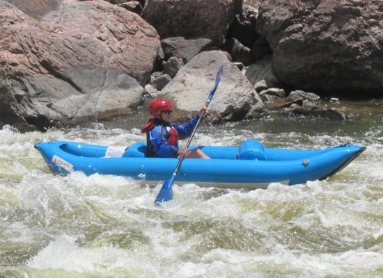 girl adventures in a raft down rapids in blue boat