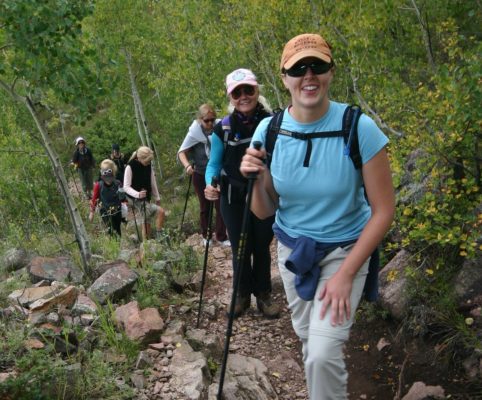 several women hiking together climbing a mountain