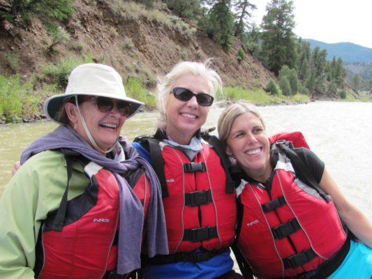 three women in life jackets on a raft trip, women's empowerment workshop